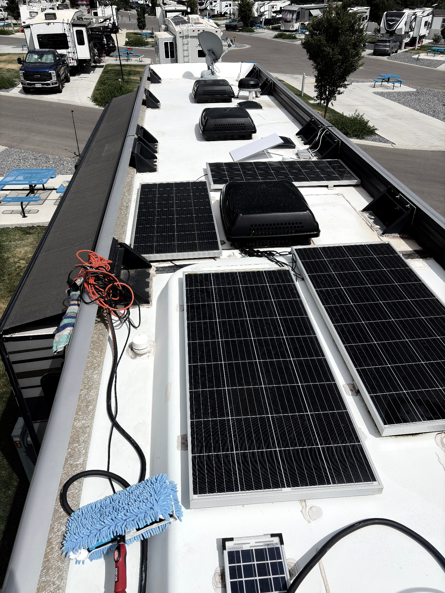 RV roof with solar panels before cleaning, dirty membrane and cleaning tools on top